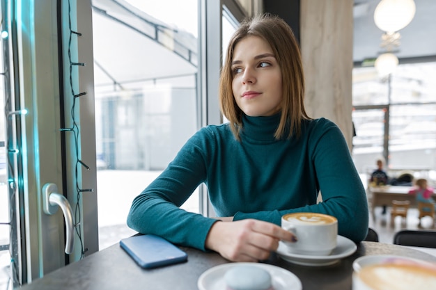 Молодая женщина отдыхает на перерыв в кафе с чашкой горячего напитка