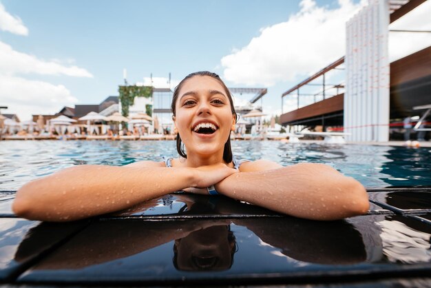 Young woman resting on the edge of swimming pool