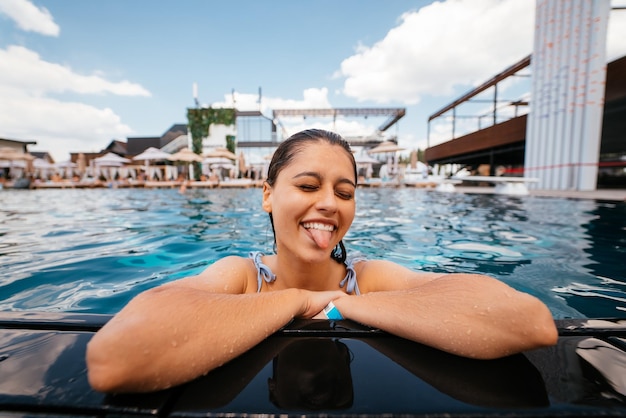 Foto giovane donna che riposa sul bordo della piscina