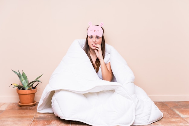 Молодая женщина отдыхает с лоскутным одеялом, кусает ногти, нервничает и очень беспокоится