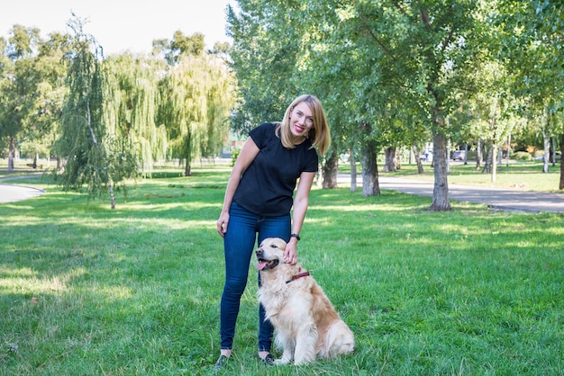 Young woman and retriever on a background of green grass in the fresh air.