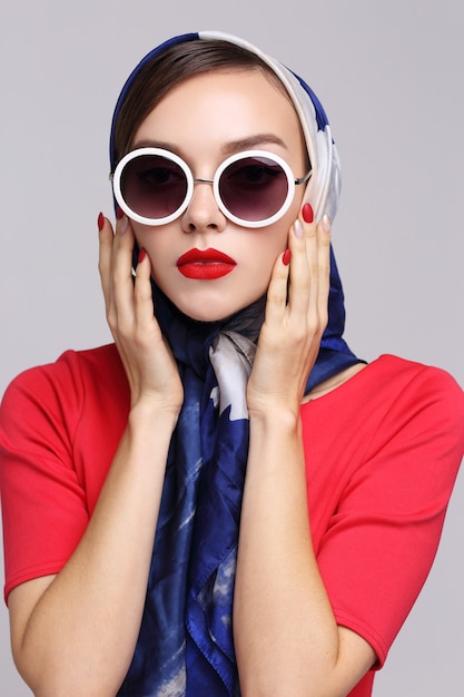 Young woman in retro style with sunglasses and silk scarf. Sixties style fashion retro woman.