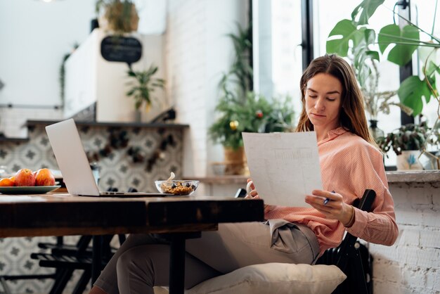 Young woman reviews documents at the kitchen table.