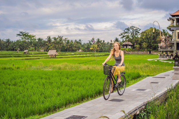 Молодая женщина едет на велосипеде по рисовому полю в Убуде Bali Bali Travel Concept