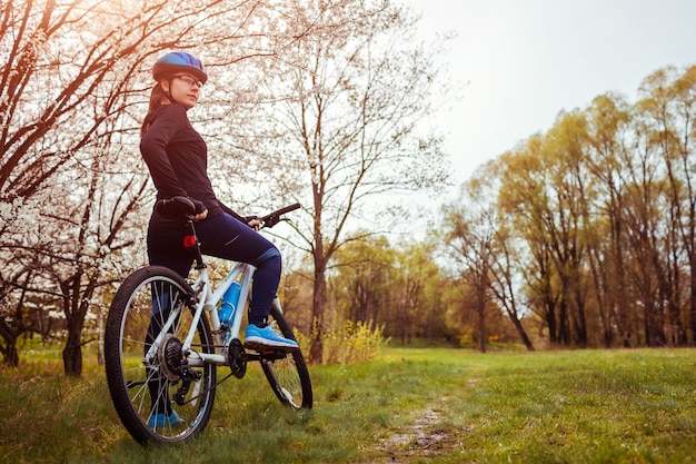 Young woman riding a bicycle in spring forest.