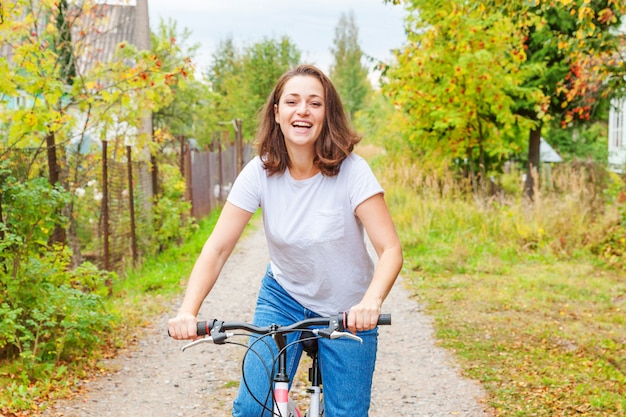 Young woman riding bicycle in summer city park outdoors