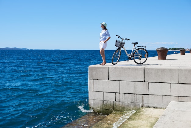 海の近くの若い女性乗馬都市自転車