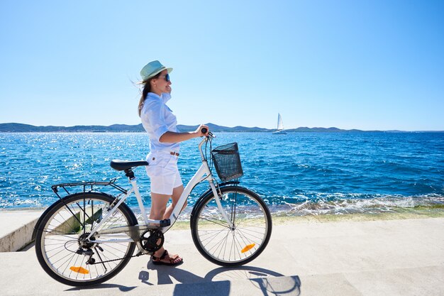 海の近くの都市の自転車に乗る若い女性