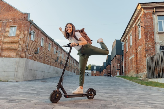 Foto giovane donna che guida uno scooter elettrico nella strada urbana della città