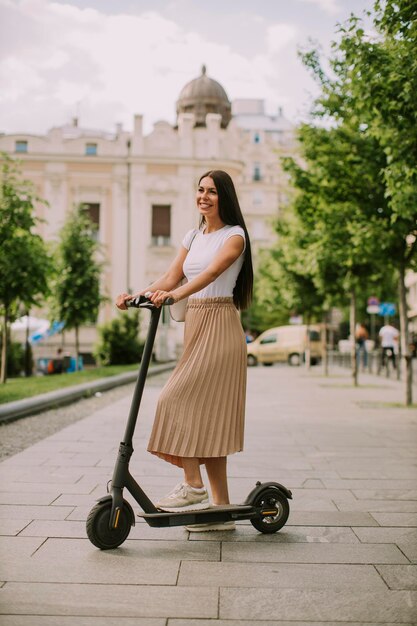 路上で電動スクーターに乗る若い女性