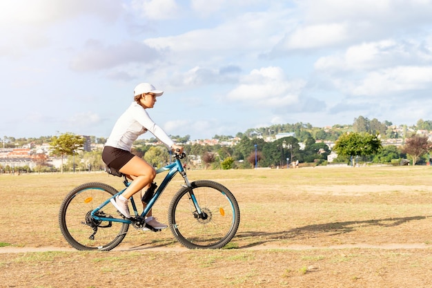 공원에서 화창한 날을 즐기는 그녀의 산악 자전거를 타는 젊은 여자.