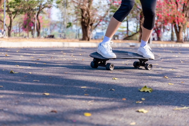 Young woman riding old-school skateboard along the street