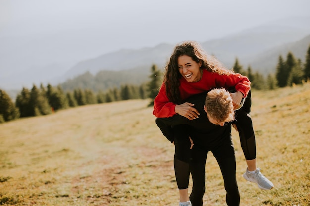 Young woman riding piggyback on a boyfriend at green hills