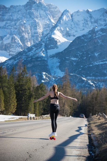 A young woman riding a skateboard towards the mountains