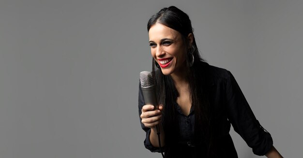 A young woman rock singer sings with a microphone in her hand while smiling