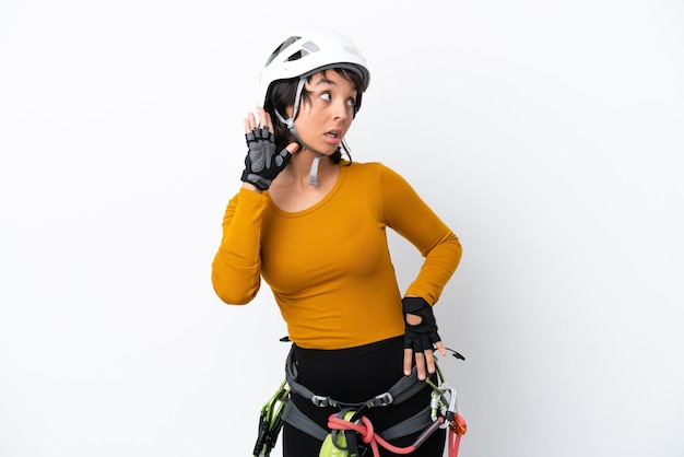 Young woman rockclimber woman isolated on white background listening to something by putting hand on the ear