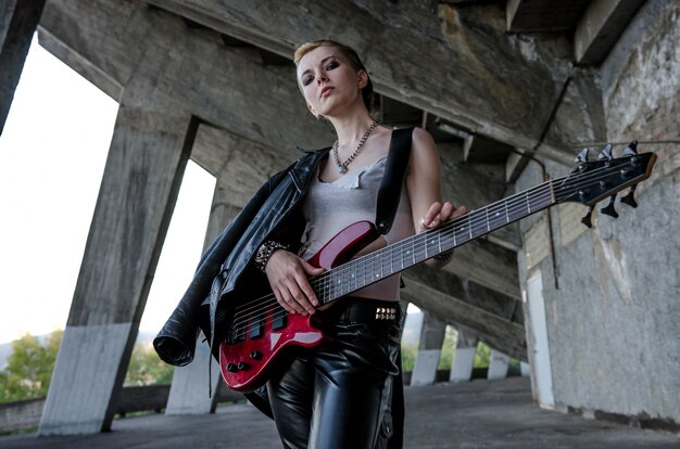 Young woman rockstar with red bass guitar