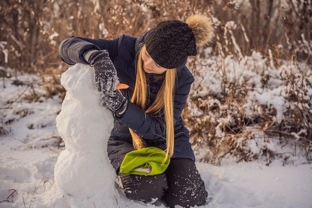 雪だるまを作るために巨大な雪玉を転がす若い女性