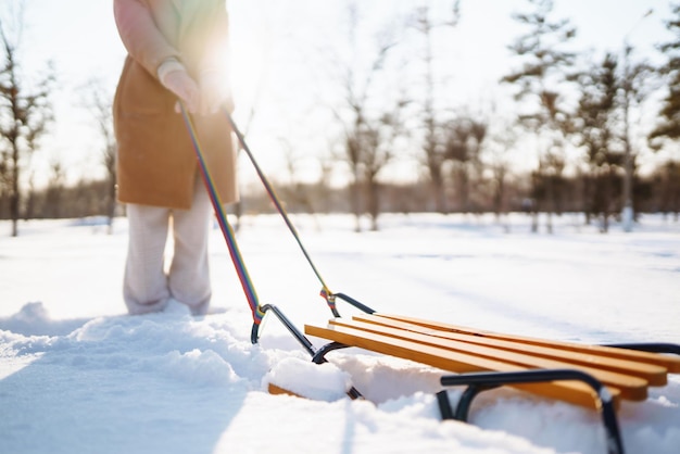 若い女性が冬の雪に覆われた森でそりに乗って転がる自然の休日の残りの旅行の概念