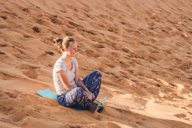 Foto giovane donna rotola su uno slittino in slitta nel deserto.