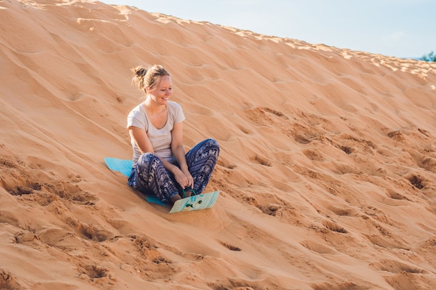 Young woman rolls on a toboggan in the sledge in the desert