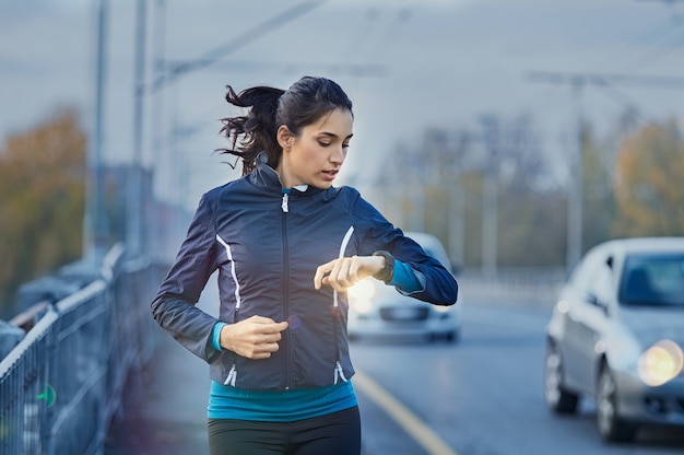 Young woman runner checking time from smart watch