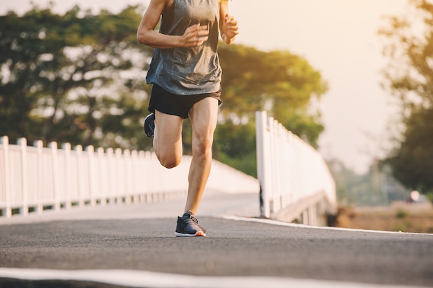 Young woman runner running on running road in city park