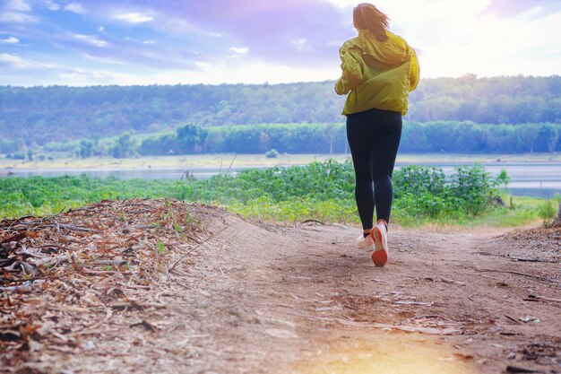 Young woman runner running trail in to a wild dry forest during\
summer on forest path