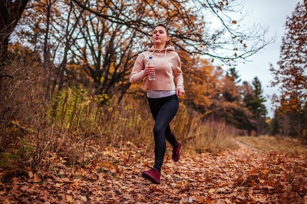 Young woman running in autumn forest. 