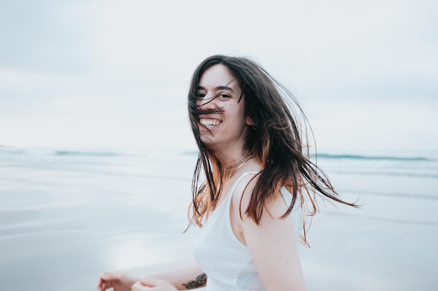 Young woman running on a paradise beach while turning around and smiling to camera carefree