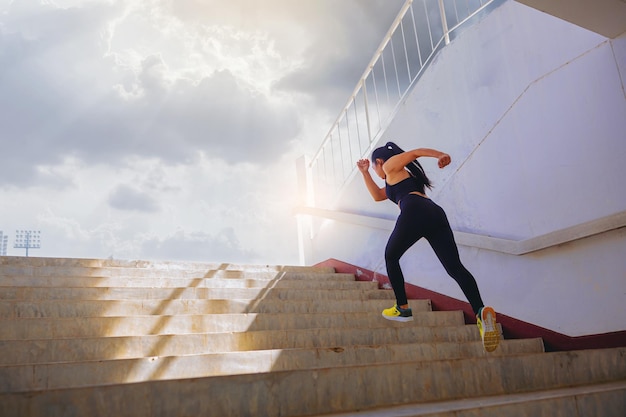 Giovane donna che corre sprint su per le scale corridore fitness in forma durante l'allenamento all'aperto