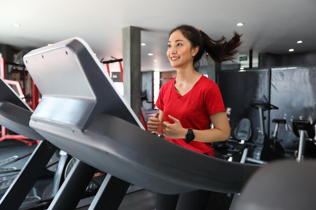 Photo young woman running on treadmill at gym