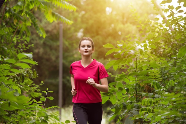 Молодая женщина, бегущая в лесистой лесной зоне, тренируется и тренируется для трейлраннинга, марафона, выносливости, фитнеса, концепции здорового образа жизни