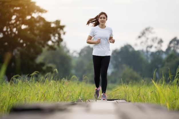 フィールドで木製の小道を走っている若い女性