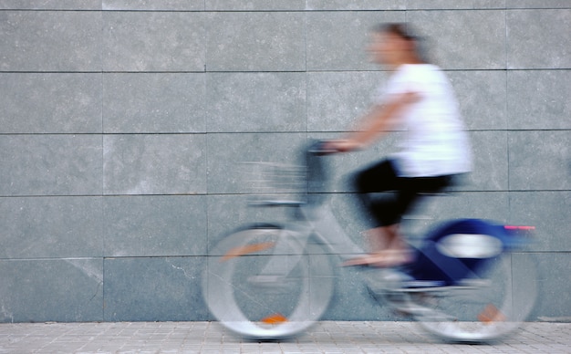 자전거에 서두르는 젊은 여자, 벽에 초점