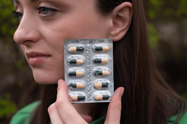 健康のためにビタミンを飲む錠剤を持つ若い女性の顔クロロフィル錠女の子ジョギング