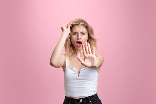 Young woman's portrait on pink studio background. Beautiful blonde model