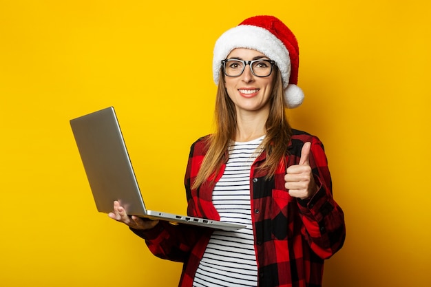 Young woman in a santa hat and a red shirt in a cage holds a laptop