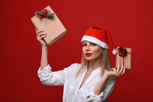 The young woman in Santa's hat and gifts in her hands.