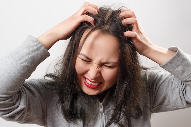 Young woman scratches her head with her fingers