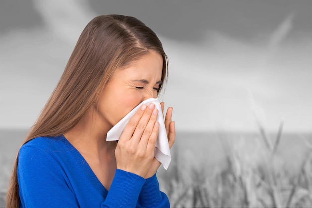 Young woman scratching her nose with elbow on  background