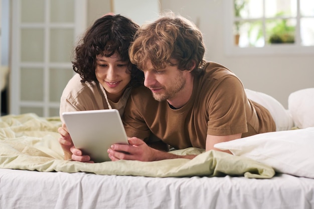 Молодая женщина прокручивает в планшете, показывая мужу онлайн-товары