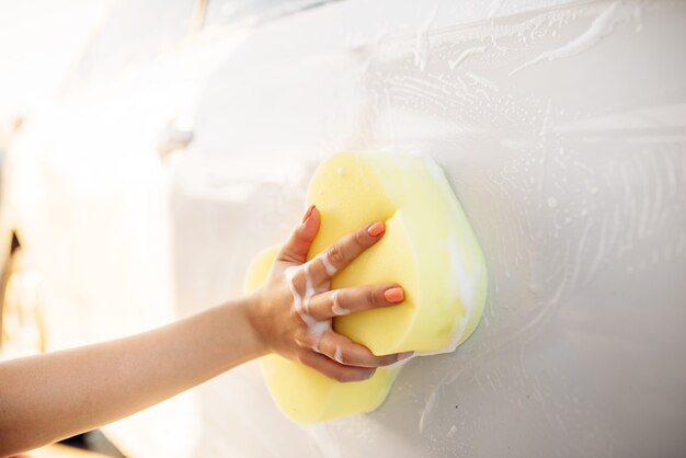 Young woman scrubbing vehicle with foam