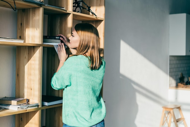 Photo young woman searching book at shelf