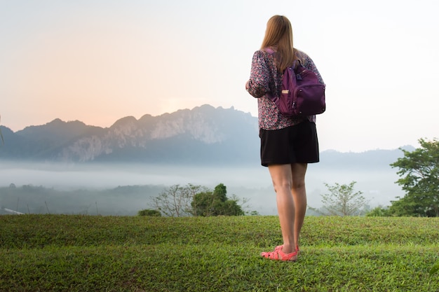 美しい山と海の雲で朝の景色を見ている若い女性