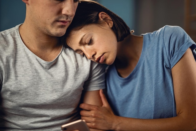 Young woman seeking for solace on boyfriend\'s shoulder while\
feeling sad about something