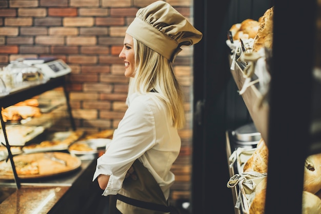 Young woman selling bread in baker shop