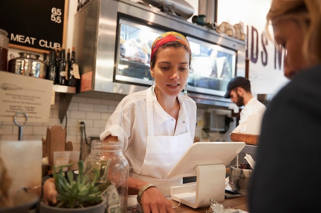 Foto giovane donna che serve un cliente in un negozio di macellaio