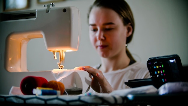 Young woman sewing a mask using a sewing machine