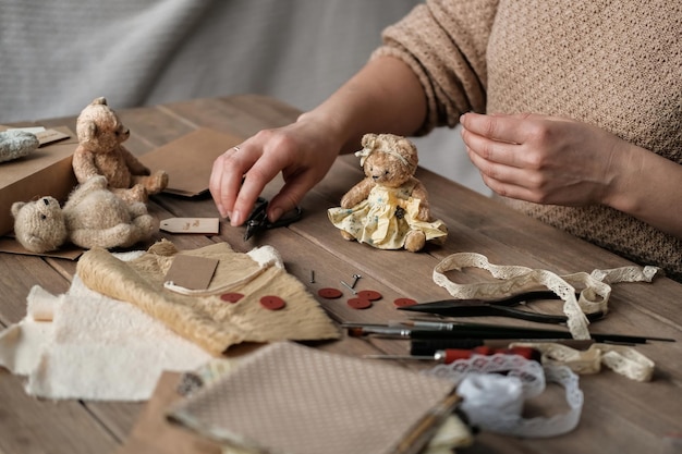 A young woman sews a teddy bear Process of making vintage toy